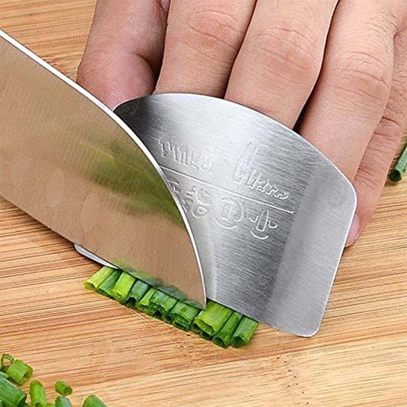 Mano con protector de dedos de acero inoxidable cortando alimentos de forma segura
